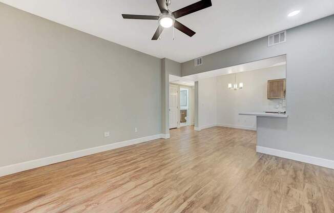 A room with a ceiling fan and wooden flooring.