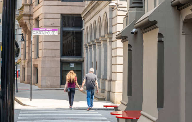 A couple walking down a sidewalk past a restaurant.