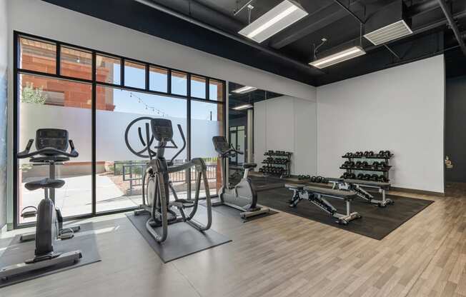 a gym with weights and other exercise equipment and a large window