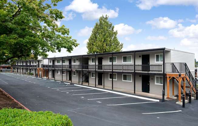 A parking lot in front of a building with a balcony.