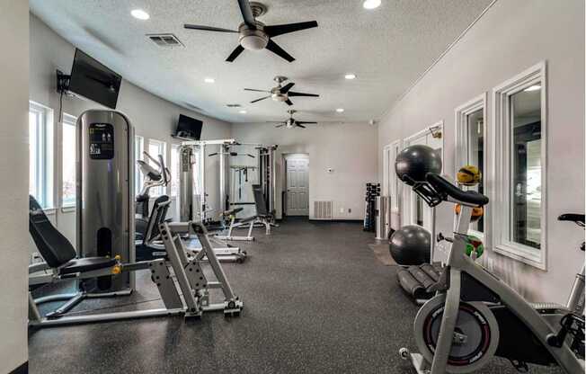 a gym with exercise equipment and a ceiling fan