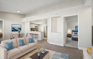 A living room with a white couch and a painting on the wall.