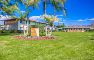 a building with palm trees and a sign in the grass