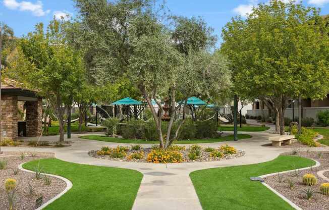 A garden with a circular flower bed in the center and a walking path around it. at The Laurel Apartments, Chandler, 85286