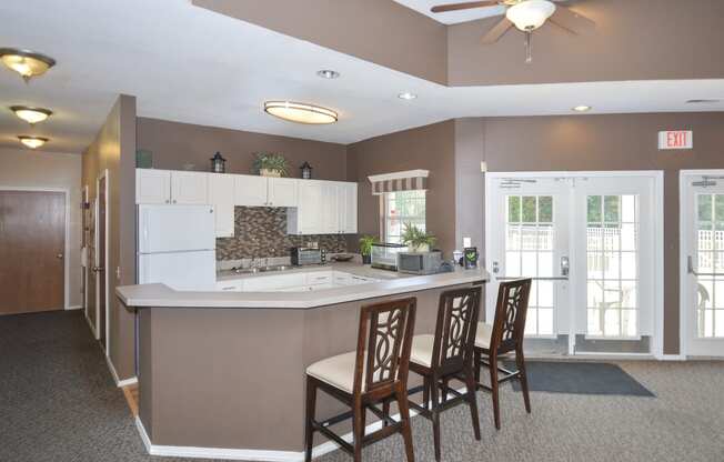 a kitchen with a counter and chairs and a ceiling fan