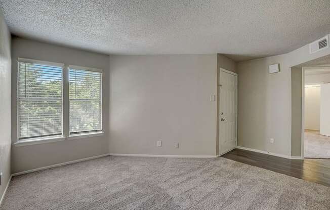 an empty living room with large windows and a door