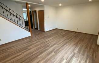 An empty living room with wooden floors and white walls