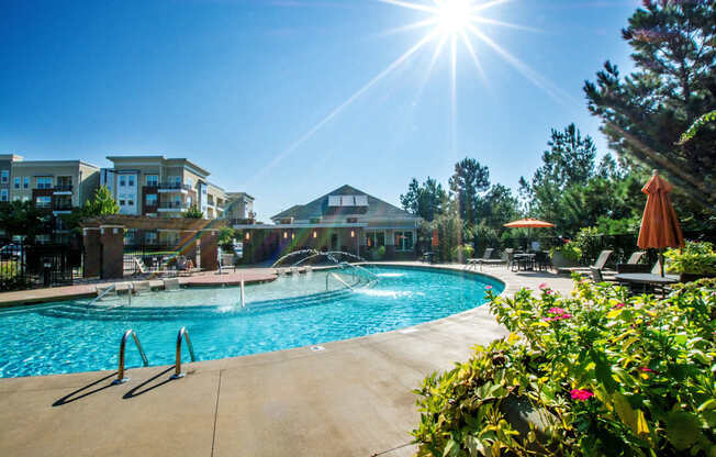 A sunny day at a poolside with a building in the background.