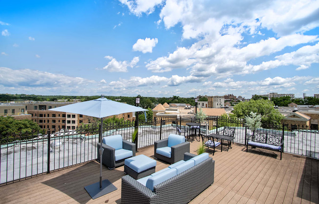 a rooftop terrace with couches and chairs and an umbrella