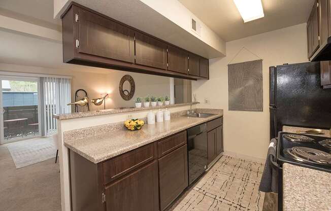Model kitchen with brown cabinets and a black refrigerator at Pheasant Pointe Apartments, California, 95833