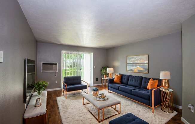 a living room with blue couches and chairs and a rug