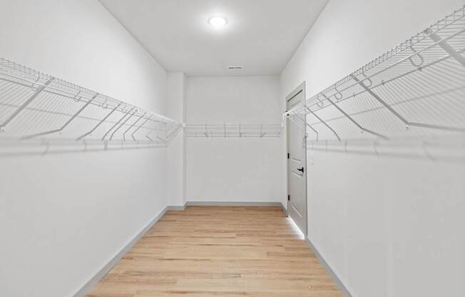 A long hallway with a white wall and a door at the end.