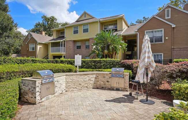 A patio with a grill and umbrella in front of a house.