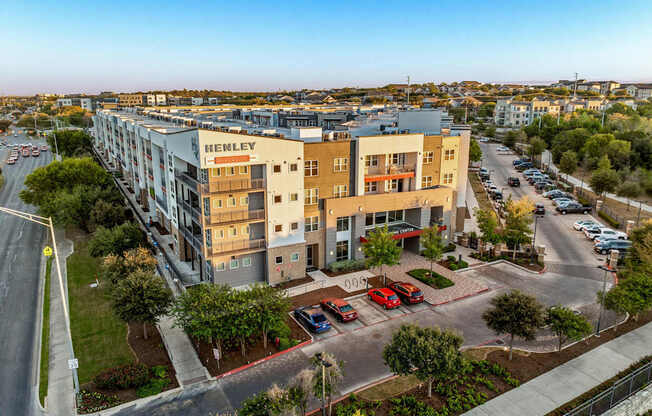 A street view of a Henley apartment complex with cars parked in the parking lot.