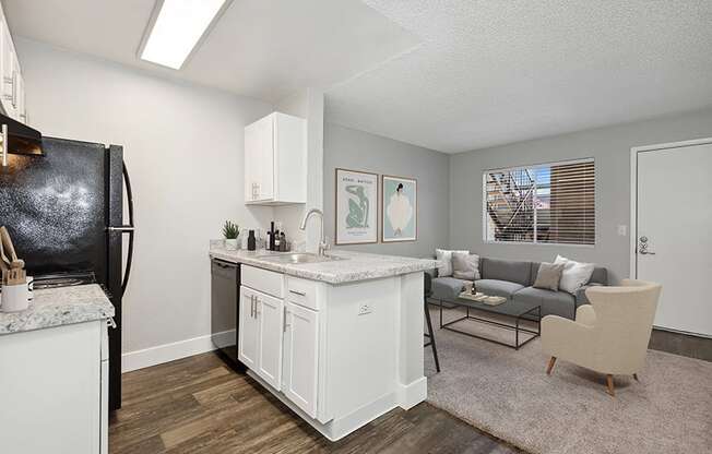 Model Kitchen with White Cabinets and Wood-Style Flooring with View of Dining Room at Stillwater Apartments in Glendale, AZ.