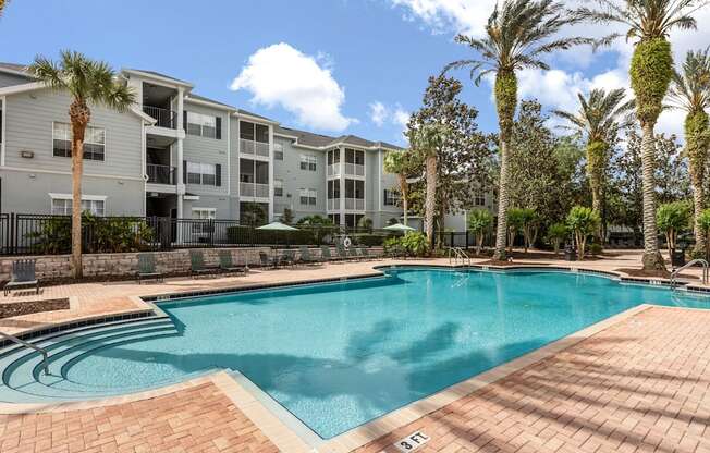 A swimming pool surrounded by palm trees and apartment buildings.