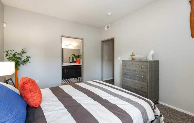 a bedroom with a bed and a dresser and a bathroom
