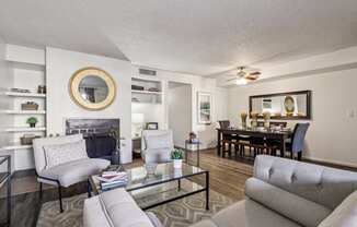 A living room with a grey couch, a glass coffee table, and a fireplace.