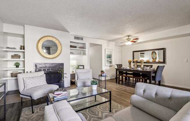 A living room with a grey couch, a glass coffee table, and a fireplace.