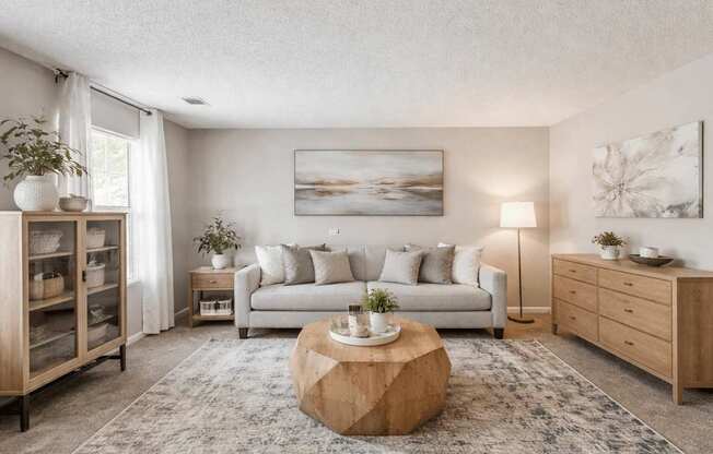 A living room with a white couch, a wooden coffee table, and a painting on the wall.