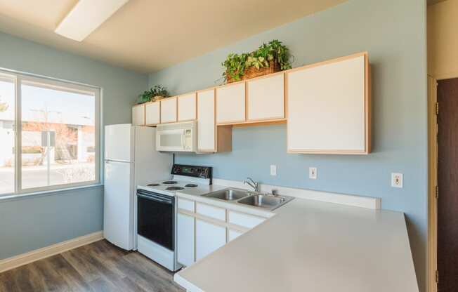 an empty kitchen with white appliances and a large window