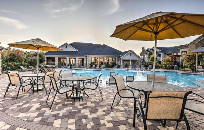 a resort style pool with tables and umbrellas at Waterstone at Cinco Ranch, Texas