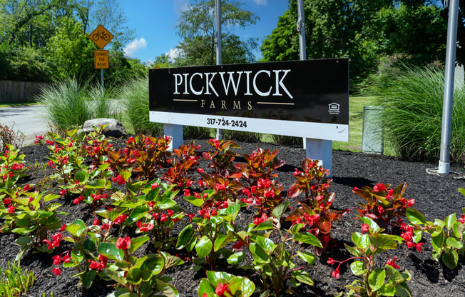 a sign for pickwick farms in front of a garden of flowers