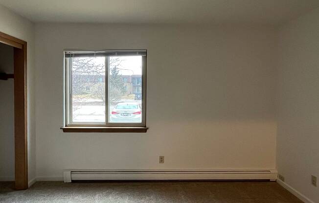 A room with a window and a white wall.
