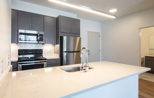 a kitchen with a white counter top and a stainless steel refrigerator