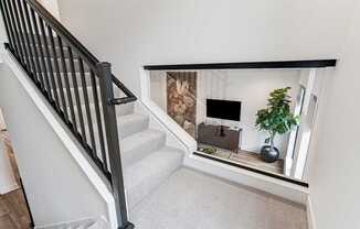 A staircase with a carpeted floor and a black railing.