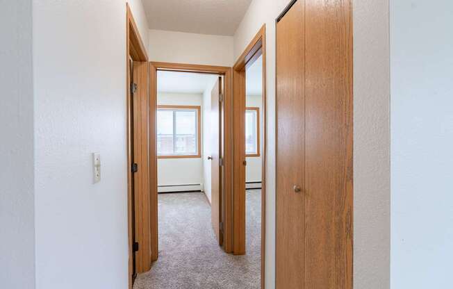 A hallway with two doors on either side leading to other rooms. West Fargo, ND Saddlebrook Apartments