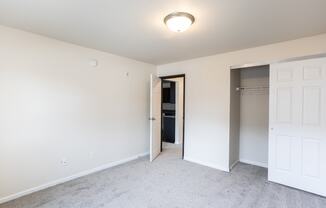 an empty bedroom with a closet and a door to a bathroom