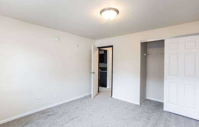 an empty bedroom with a closet and a door to a bathroom