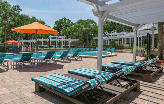 a pool area with lounge chairs and umbrellas
