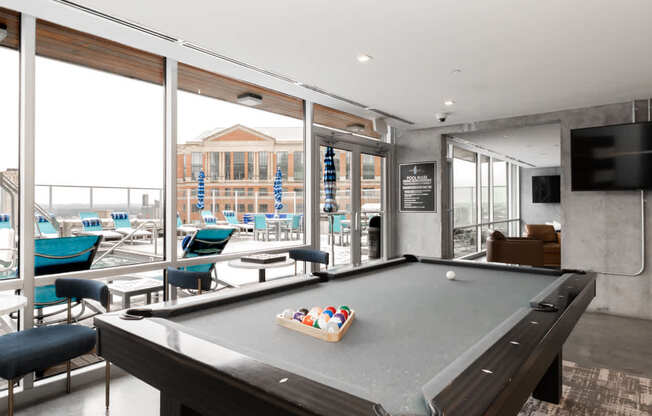 A pool table in a room with a view of the outside.