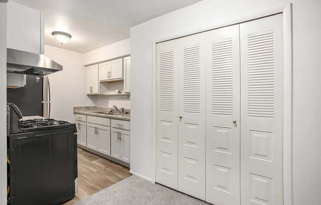 A kitchen with white cabinets and a large closet at Brookside Apartments, Springfield