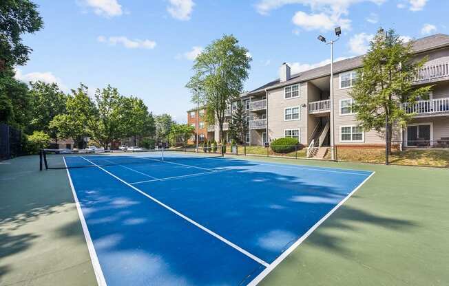 a tennis court with an apartment building in the background