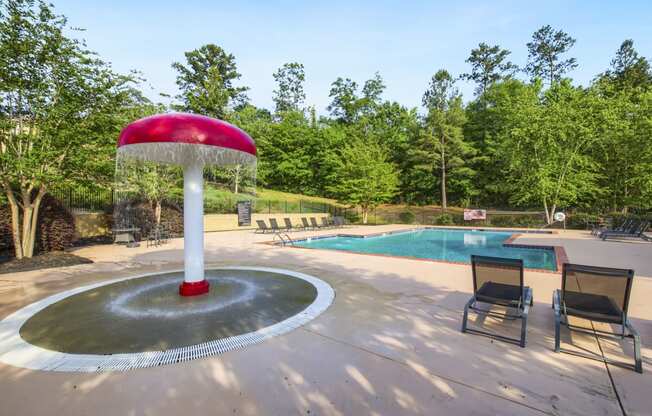 a fountain with a red umbrella next to a pool