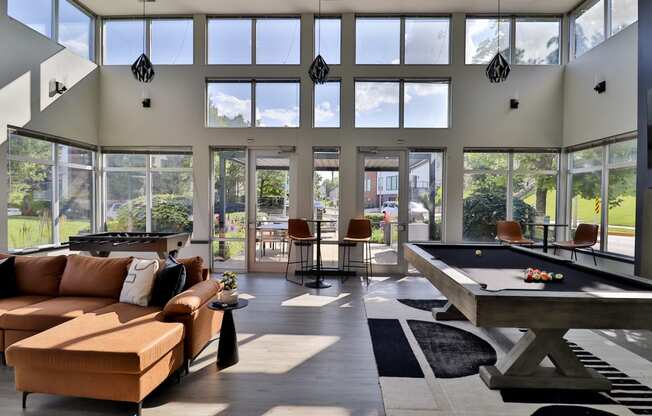 a large living room with a pool table and large windows