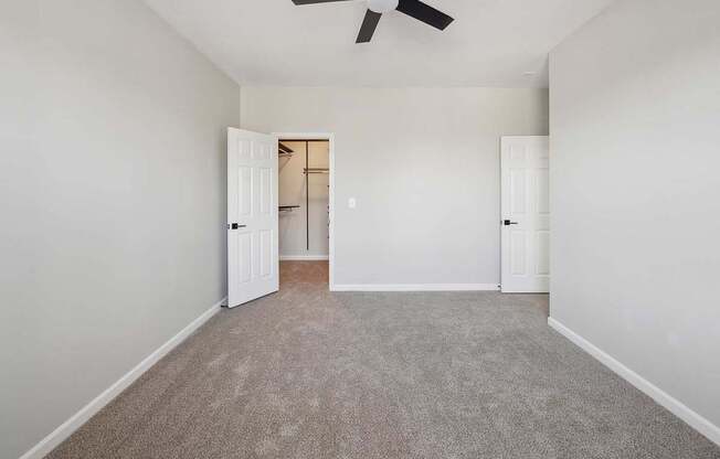 A room with a ceiling fan and carpeted floor.