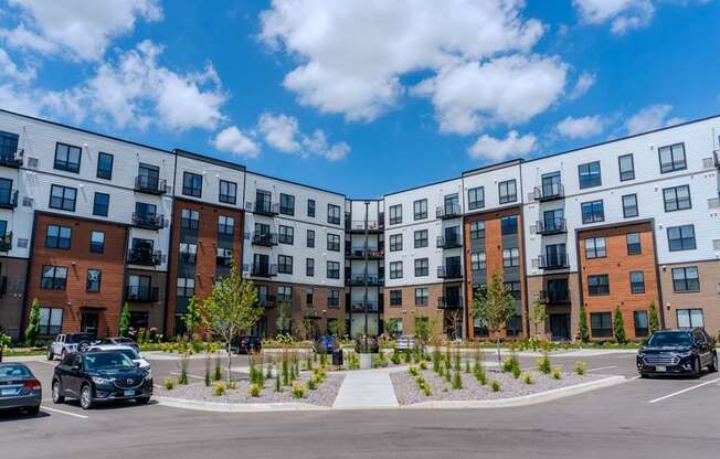 A row of modern apartment buildings with cars parked in front.