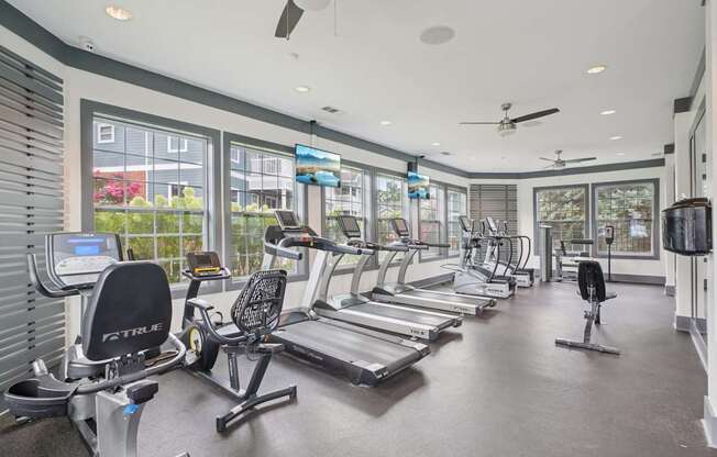 A gym with treadmills, exercise bikes, and a television.