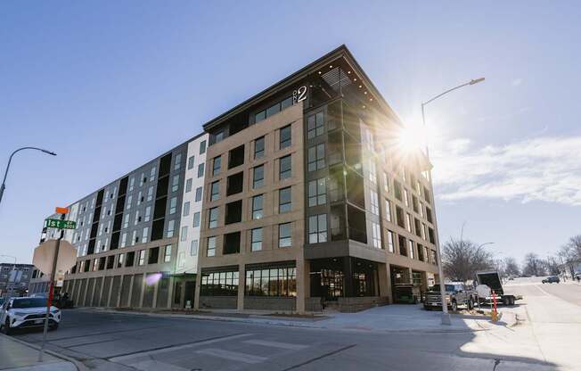 A modern building with a glass facade is bathed in sunlight.