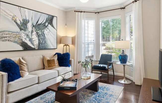 A living room with a white couch, a coffee table, and a painting on the wall.