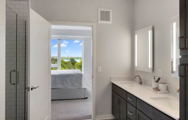 a bathroom with a large window and a bed in the background
