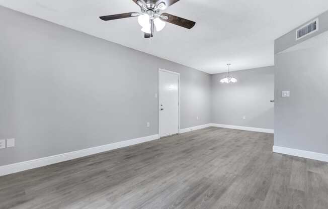 the living room of an empty house with a ceiling fan