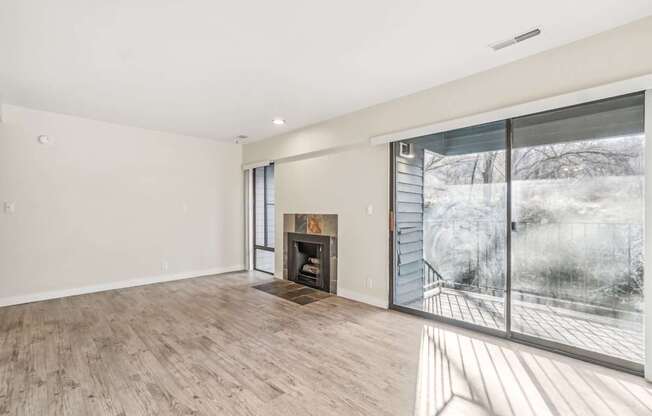 A large, empty room with a fireplace and a view of a snowy landscape outside.