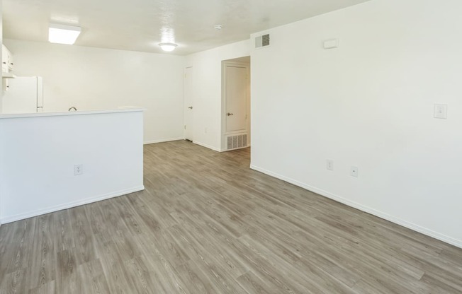 an empty living room with white walls and wood flooring