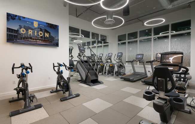 a gym with various exercise equipment and a tv on the wall