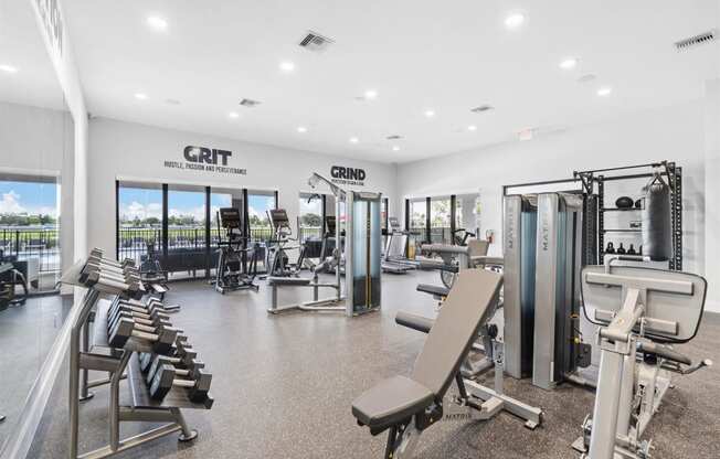 a gym with cardio equipment and weights in a building with windows